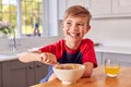 Boy At Home Eating Bowl Of Breakfast Cereal At Kitchen Counter Royalty Free Stock Photo