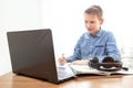 A boy at home in front of a computer does his homework. Distance learning in quarantine. Notebooks and headphones are on the table