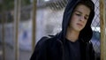 Boy in hoodie leaning on fence, orphan in boarding school, confinement