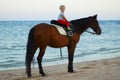 A boy on horseback rides on the beach. Cute little boy looking at camera.