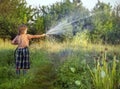 Boy hose garden on summer day