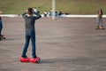 Boy on a hoverboard trying to walk on it with hands on head, looks confused