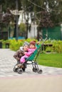 Boy hugging baby girl sitting in a stroller. Brother and sister on a stroll in the park, lovely autumn day. Looking at the camera. Royalty Free Stock Photo