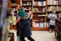 Boy in jacket reaching a book from bookshelf at the library. Learning and education of european kids Royalty Free Stock Photo