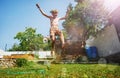 Boy jump over water sprinkler with hands up at garden lawn Royalty Free Stock Photo