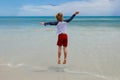 Boy jumping on the beach in front of ocean waves