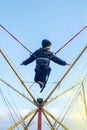 The boy is jumping on a bungee trampoline. A child with insurance and stretchable rubber bands hangs against the sky. The concept Royalty Free Stock Photo