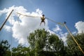 The boy is jumping on a bungee trampoline. A child with insurance and stretchable rubber bands hangs against the sky. The concept Royalty Free Stock Photo