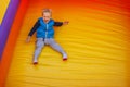 Happy little boy sliding down an a yellow- orange inflatable slide. There is free space for text in the image Royalty Free Stock Photo