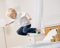 Boy jumping in mid-air on bed in bedroom Royalty Free Stock Photo