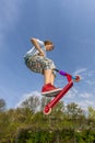 Boy is jumping with a scooter over a spine in the skate parc