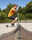 Boy is jumping with a scooter over a spine in the skate parc and