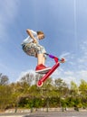 Boy is jumping with a scooter over a spine in the skate park