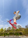 Boy is jumping with a scooter over a spine in the skate park