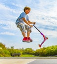 Boy is jumping with a scooter over a spine in the skate park