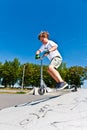 Boy is jumping with scooter in a skatepark