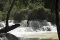 boy jumping into the water at the Kuang Si natural park waterfalls in Luang Prabang