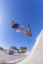 Boy jumps with his scooter over a ramp