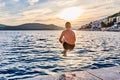 The boy jumps into the sea from a stone pier at sunset Royalty Free Stock Photo