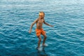 Boy jumps from stone pier to sea touching water