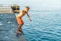 Boy jumps into tranquil ocean water from stone pier