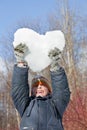 Boy keeps in hands hearts from snow over head