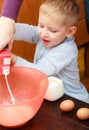 Boy kid baking cake. Child pouring mik into a bowl. Kitchen.