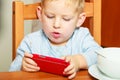 Boy kid child eating corn flakes breakfast playing mobile phone Royalty Free Stock Photo
