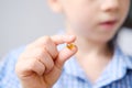 Boy kid holds a capsule with fish oil in gelatin in his hand, the concept of children`s health, avitaminosis, treatment