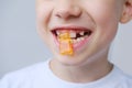 Boy, kid holds in his mouth and eats gelatinous sweets, gummy bear, concept of children`s delicacy, healthy and unhealthy food,