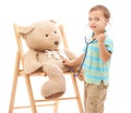 Boy kid, teddy bear and stethoscope in studio for playing doctor, listening and wellness by white background. Child Royalty Free Stock Photo