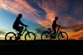 Boy , kid 10 years old, and girl riding bikes in countryside in amazing colorful cloudy night sky background Royalty Free Stock Photo