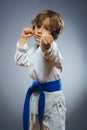 Boy in kimono during training karate exercises isolated on gray background Royalty Free Stock Photo