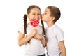 Boy kisses little girl with candy red lollipop in heart shape isolated on white Royalty Free Stock Photo