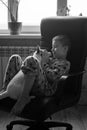 a boy kisses playing at home with a Jack Russell dog by the window. black and white photo. vertical