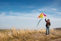 A boy with a kite against the blue sky. Bright sunny day. Strong wind. A boy of European appearance, dressed in jeans and a black Royalty Free Stock Photo