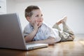 Boy with laptop computer laying down on the floor Royalty Free Stock Photo