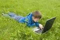 Boy with laptop computer on meadow.