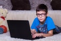 A boy with a laptop lying on the floor at home, on the carpet. Technology, Internet, modern communication concept Royalty Free Stock Photo