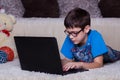 A boy with a laptop lying on the floor at home, on the carpet. Technology, Internet, modern communication concept Royalty Free Stock Photo