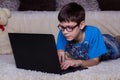 A boy with a laptop lying on the floor at home, on the carpet. Technology, Internet, modern communication concept Royalty Free Stock Photo