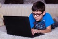 A boy with a laptop lying on the floor at home, on the carpet. Technology, Internet, modern communication concept Royalty Free Stock Photo