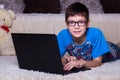 A boy with a laptop lying on the floor at home, on the carpet. Technology, Internet, modern communication concept Royalty Free Stock Photo