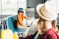 Boy with laptop waving at preteen kid in waiting hall Royalty Free Stock Photo