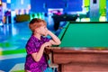 The boy is leaning on a pool table and waiting with someone to play table billiards Royalty Free Stock Photo