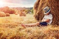 Boy leaning and sleeping against a haystack at sunset Royalty Free Stock Photo
