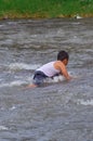 Boy leans down to pick something from river current Royalty Free Stock Photo