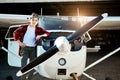 Boy leans on plane near aircraft hangar, stands with serious face expression