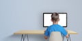 Boy learn to code on desktop computer concept. A boy in a blue shirt with his back turned