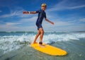 Boy learn to stand on the surf board standing at sea beach Royalty Free Stock Photo